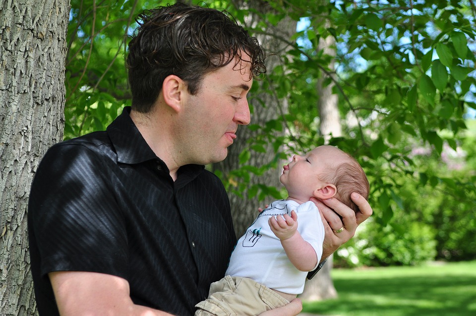 Father holding baby, both have tongues out!